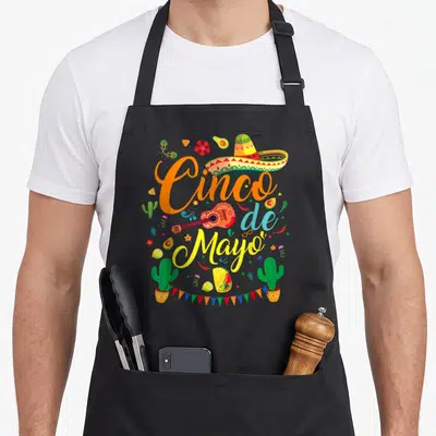 Cinco mayo mexican apron - Cinco de Mayo text with sombrero guitar tacos cacti bunting flags in cartoon style — shown on a black cotton canvas apron against a white background