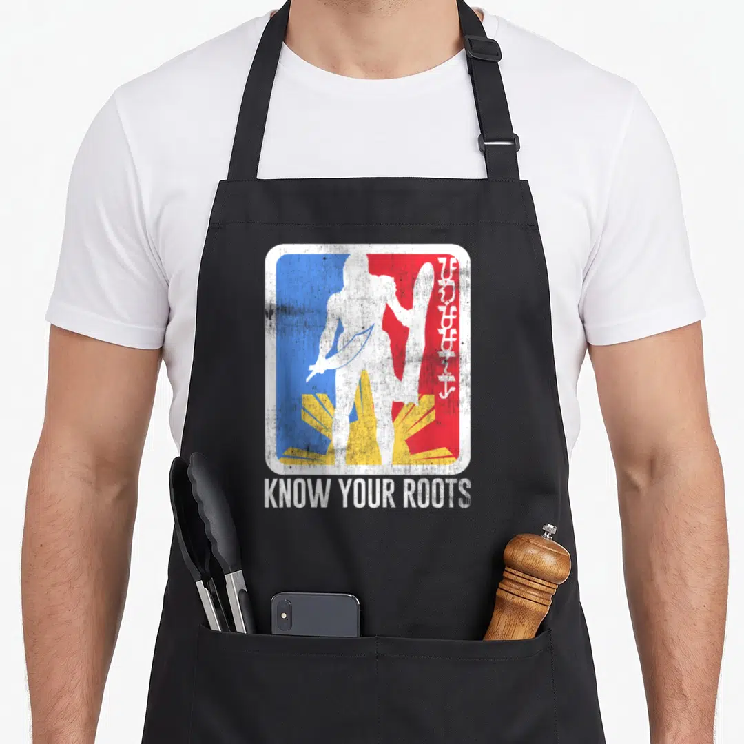 Lapu pride apron - White warrior silhouette with sword and shield over blue red yellow rays above KNOW YOUR ROOTS text — shown on a black cotton canvas apron against a white background