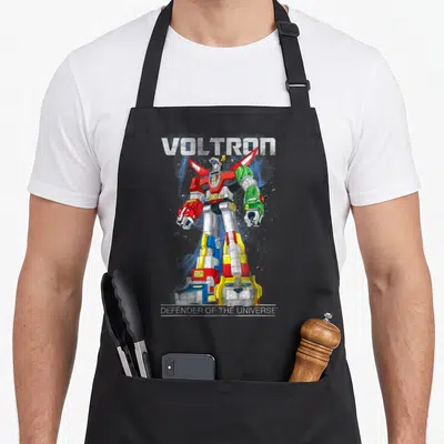Voltron distressed apron - Red blue yellow and white robot with VOLTRON text and distressed lettering — shown on a black cotton canvas apron against a white background