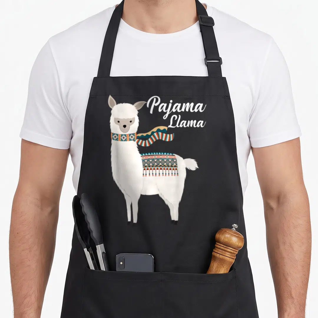 Pajama bed apron - Cartoon white llama with patterned scarf and blanket in teal orange brown — shown on a black cotton canvas apron against a white background