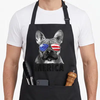 French bulldog 4th of july apron - Realistic French Bulldog head wearing sunglasses with USA flag reflection and merica — shown on a black cotton canvas apron against a white background