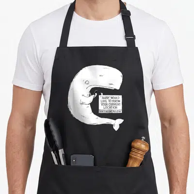 Bump cartoon apron - White whale holding phone with Ahab location notification text in black and white cartoon style — shown on a black cotton canvas apron against a white background