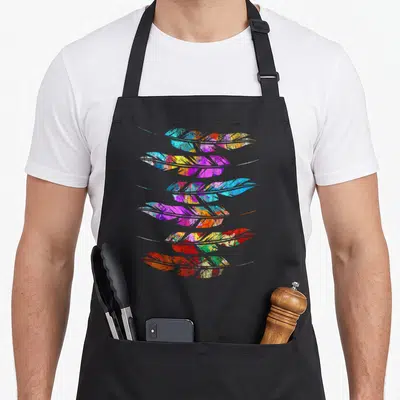 Heritage native american aprons - Six multicolored watercolor feathers stacked vertically in blue purple yellow red — shown on a black cotton canvas apron against a white background