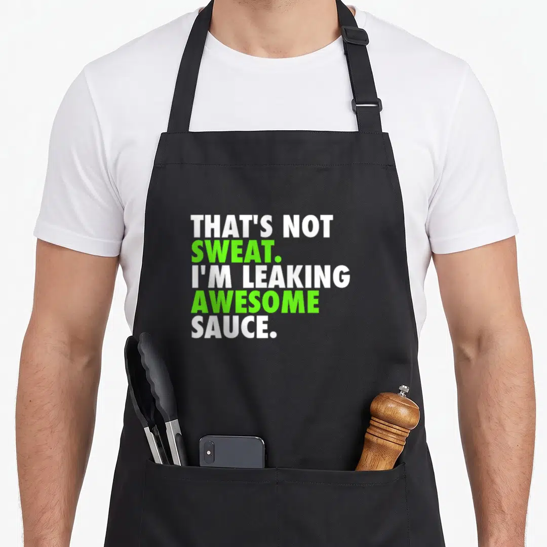 Sweat funny sauce apron - Stacked white and lime green text reading That's Not Sweat I'm Leaking Awesome Sauce — shown on a black cotton canvas apron against a white background