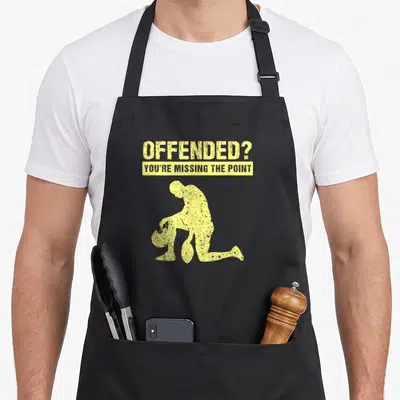 Protest peaceful apron - Yellow distressed text above kneeling football player silhouette holding helmet — shown on a black cotton canvas apron against a white background
