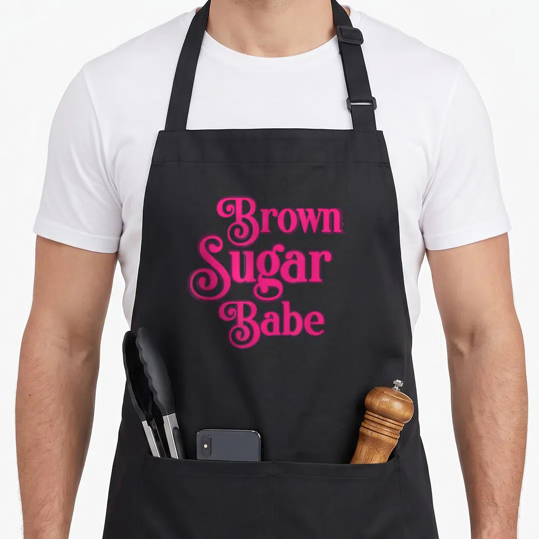 Melanin skin african american aprons - Pink stacked typography reading Brown Sugar Babe celebrating brown skin — shown on a black cotton canvas apron against a white background