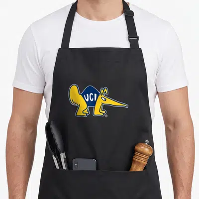 Cal cardinal dad apron - Cartoon anteater in yellow and blue with UCI text on torso — shown on a black cotton canvas apron against a white background