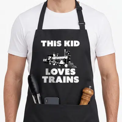 Locomotive engineer apron - Black steam locomotive illustration centered between white text reading THIS KID LOVES — shown on a black cotton canvas apron against a white background