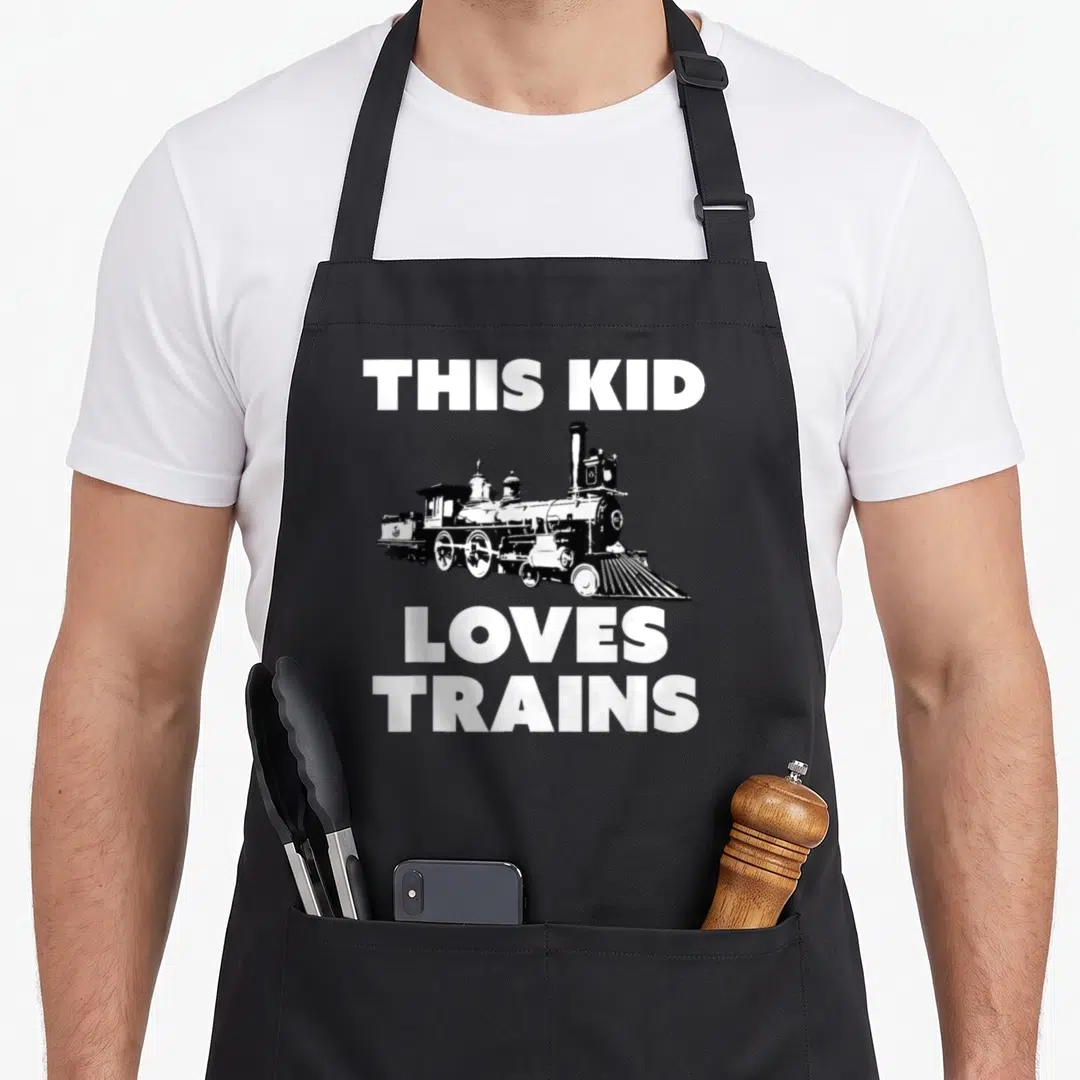 Locomotive engineer apron - Black steam locomotive illustration centered between white text reading THIS KID LOVES — shown on a black cotton canvas apron against a white background