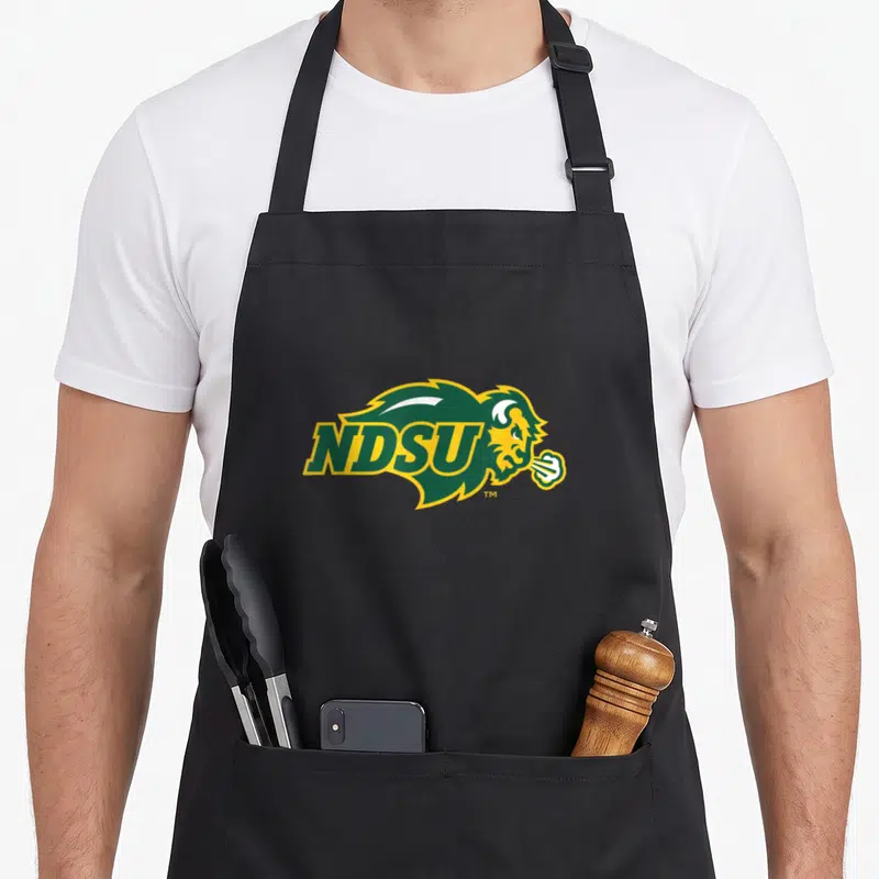 North bison apron - NDSU logo over bison profile with steam in green yellow white — shown on a black cotton canvas apron against a white background