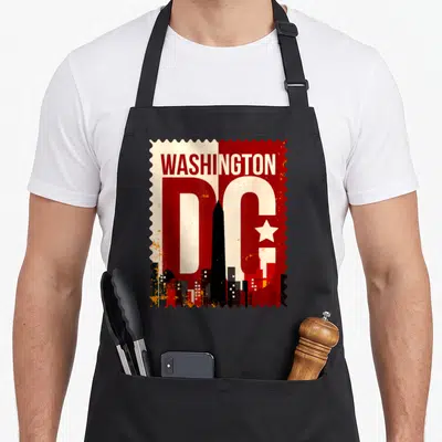 Souvenir washington boy apron - Red cream stamp graphic with WASHINGTON DC text, black monument silhouette, and white — shown on a black cotton canvas apron against a white background