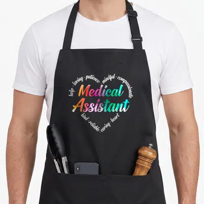 Medical rainbow apron - Medical Assistant text in watercolor rainbow colors surrounded by white virtue words forming — shown on a black cotton canvas apron against a white background
