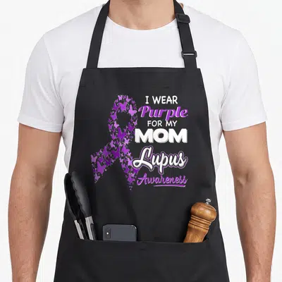 Funny lupus awareness apron - Purple butterfly awareness ribbon next to stacked text reading I WEAR Purple FOR MY MOM — shown on a black cotton canvas apron against a white background