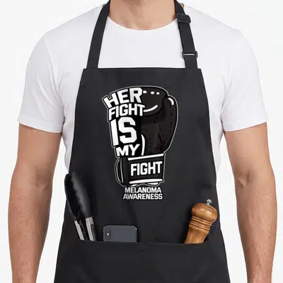 Hyperpigmentation melanoma awareness apron - Black boxing glove with Her Fight Is My Fight and Melanoma Awareness text — shown on a black cotton canvas apron against a white background