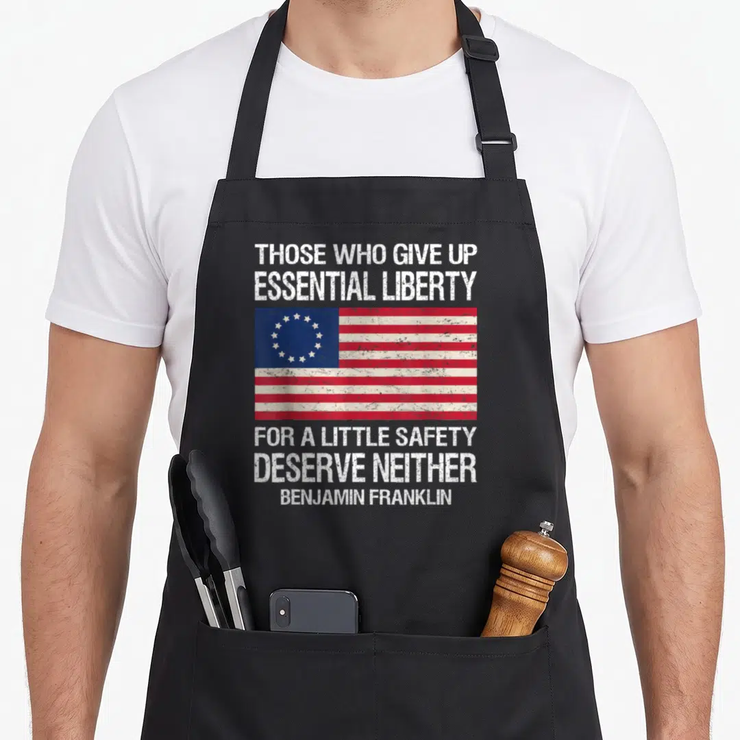 Those safety apron - Distressed white quote text surrounding a circular star Betsy Ross flag in red white and blue — shown on a black cotton canvas apron against a white background