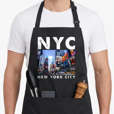 Sleep new york apron - White NYC text above and below a photo of Times Square billboards and taxis — shown on a black cotton canvas apron against a white background