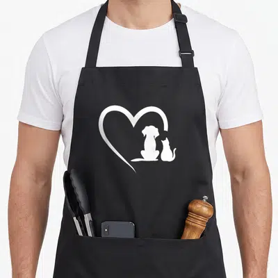 Dog cat apron - White heart outline enclosing dog and cat silhouettes on grey background — shown on a black cotton canvas apron against a white background
