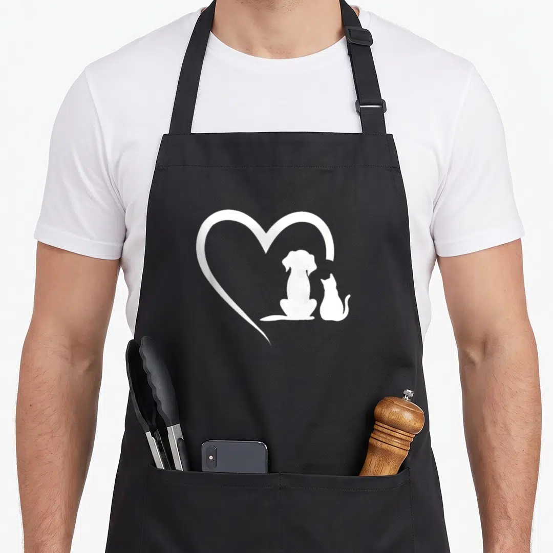 Dog cat apron - White heart outline enclosing dog and cat silhouettes on grey background — shown on a black cotton canvas apron against a white background