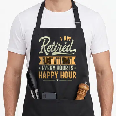 Retired flight attendant apron - Stacked distressed text reading I AM Retired FLIGHT ATTENDANT EVERY HOUR IS HAPPY HOUR — shown on a black cotton canvas apron against a white background