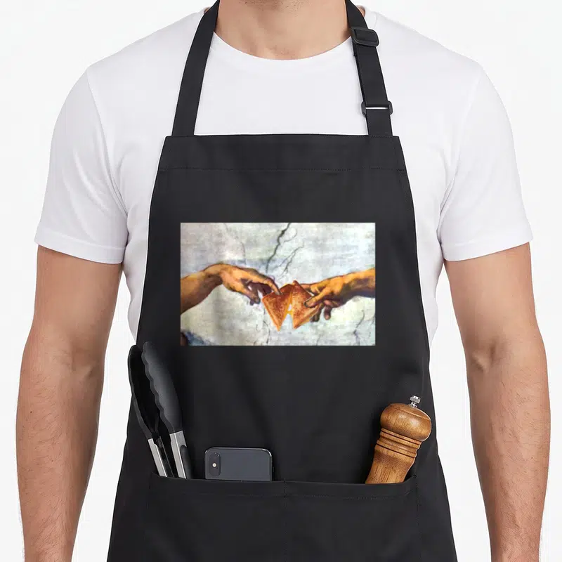 Creation cheese apron - Two hands reaching for a split grilled cheese sandwich in fresco style — shown on a black cotton canvas apron against a white background