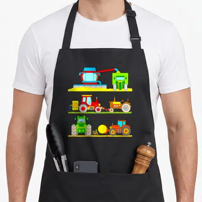 Tractor harvester combine apron - Three rows of cartoon tractors and harvester in red yellow green and blue — shown on a black cotton canvas apron against a white background