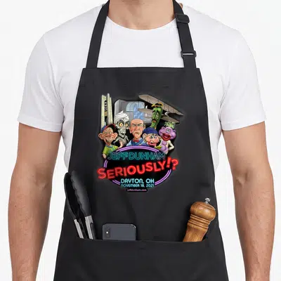Jeff dayton apron - Puppet cluster above stacked neon text reading Jeff Dunham seriously Dayton Ohio — shown on a black cotton canvas apron against a white background