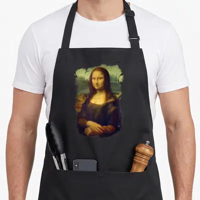 Mona stylish apron - Centered portrait of Mona Lisa with rough painted edges in brown, gold, green, and blue — shown on a black cotton canvas apron against a white background