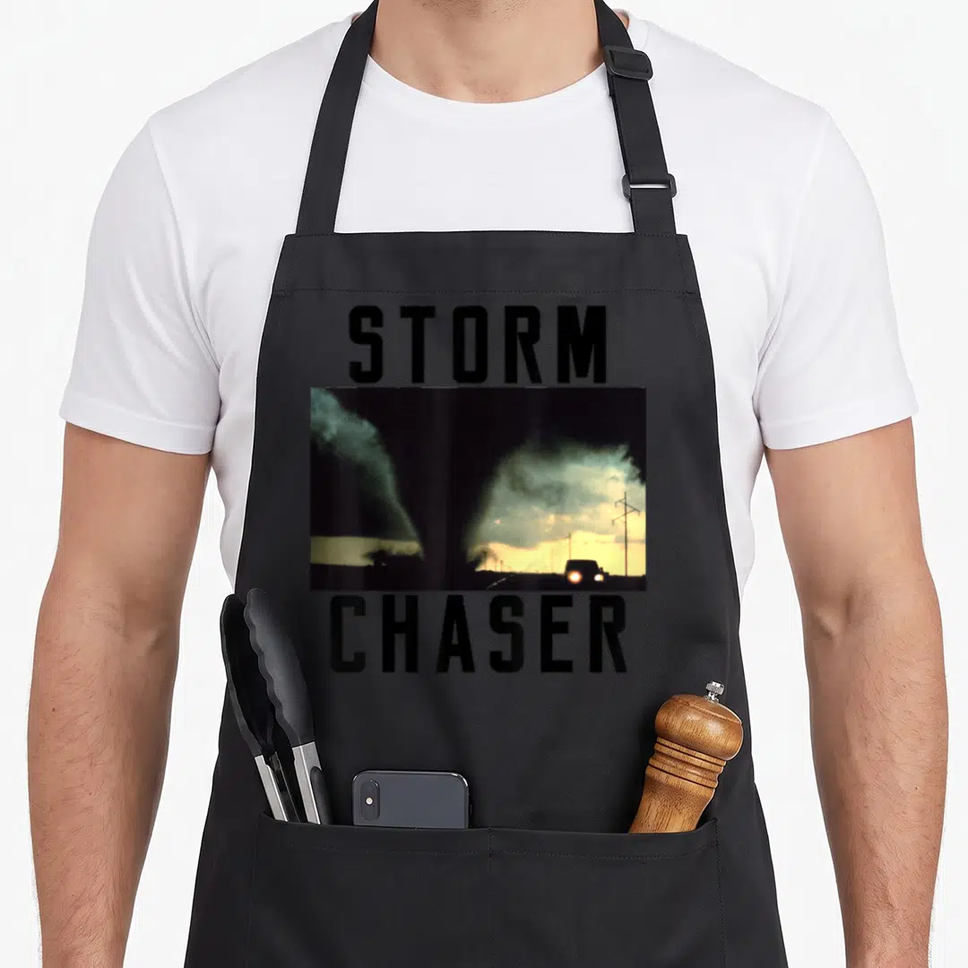 Storm meteorologist apron - Photo of tornado and car with STORM CHASER text in black and yellow — shown on a black cotton canvas apron against a white background
