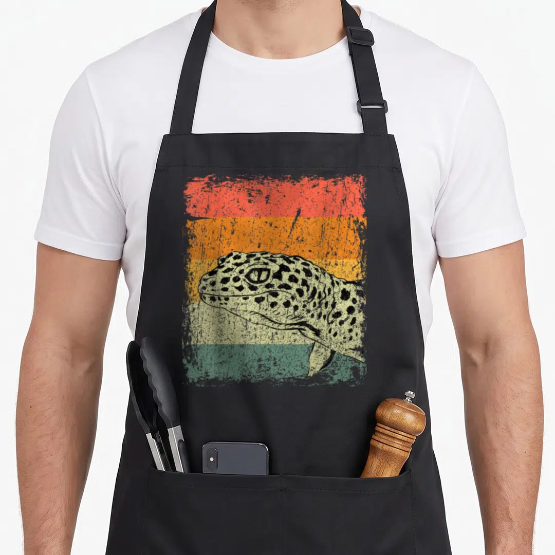 Lizard salamander apron - Spotted leopard head over four distressed horizontal stripes in red orange yellow green beige — shown on a black cotton canvas apron against a white background