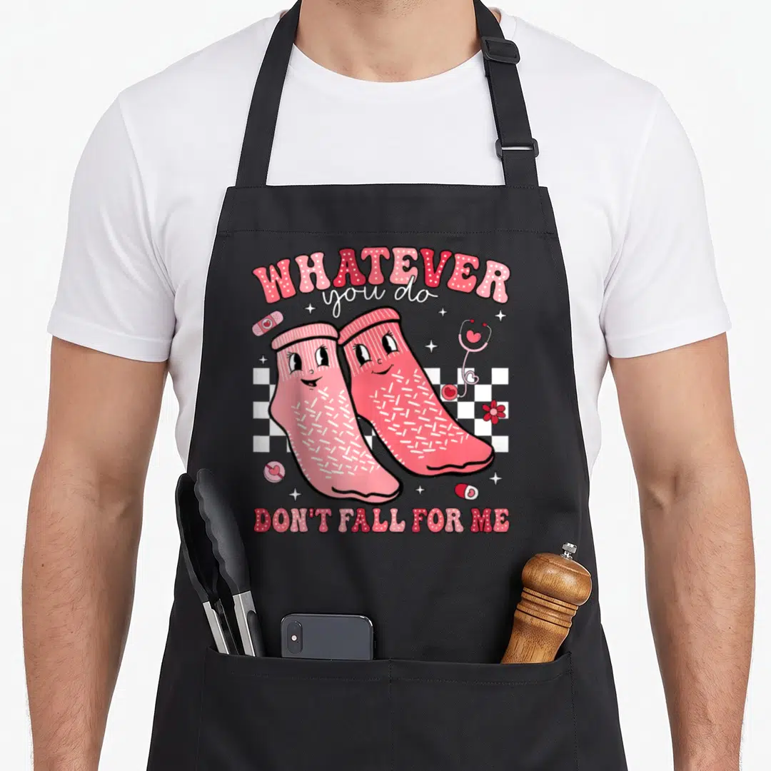 Valentine fall apron - Two pink cartoon socks on checkerboard with medical icons and text whatever you do don't fall — shown on a black cotton canvas apron against a white background