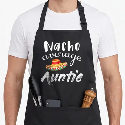Nacho guacamole apron - Sombrero filled with chips and text reading Nacho average Auntie — shown on a black cotton canvas apron against a white background