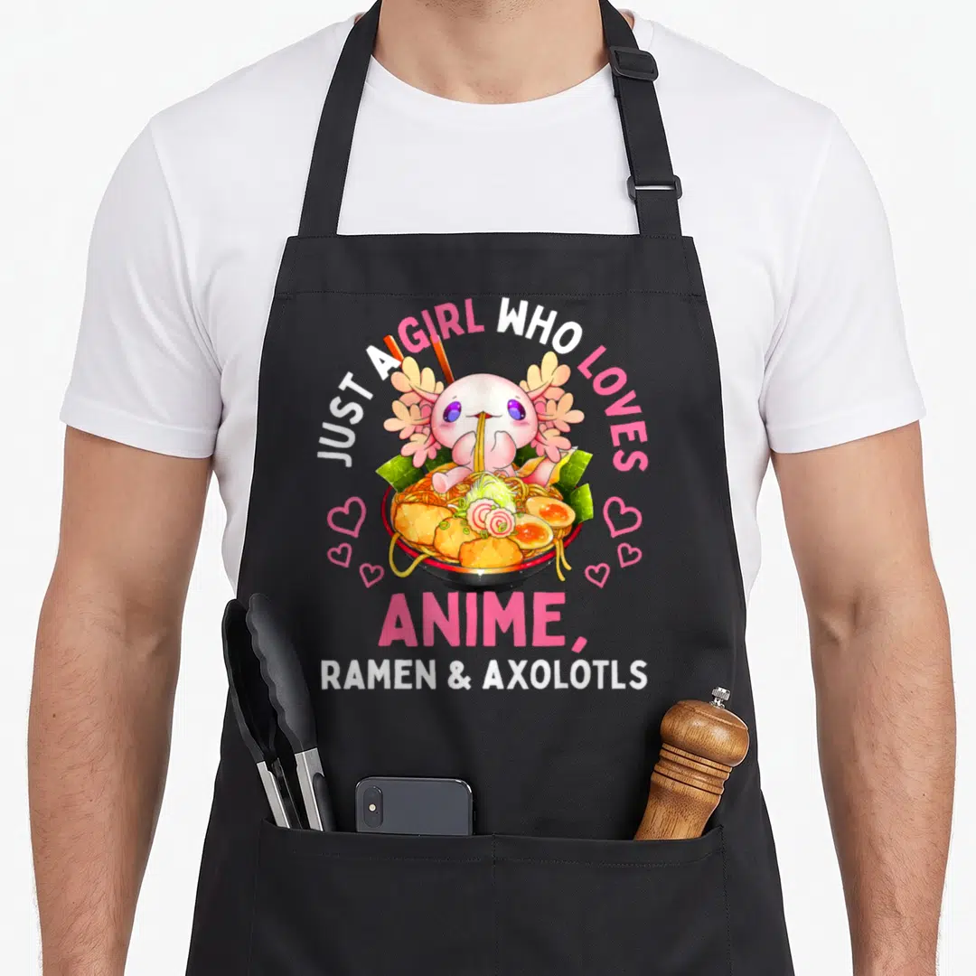 Anime ramen kawaii cooking apron - Cartoon axolotl in ramen bowl with arched pink and white text reading Just a Girl — shown on a black cotton canvas apron against a white background
