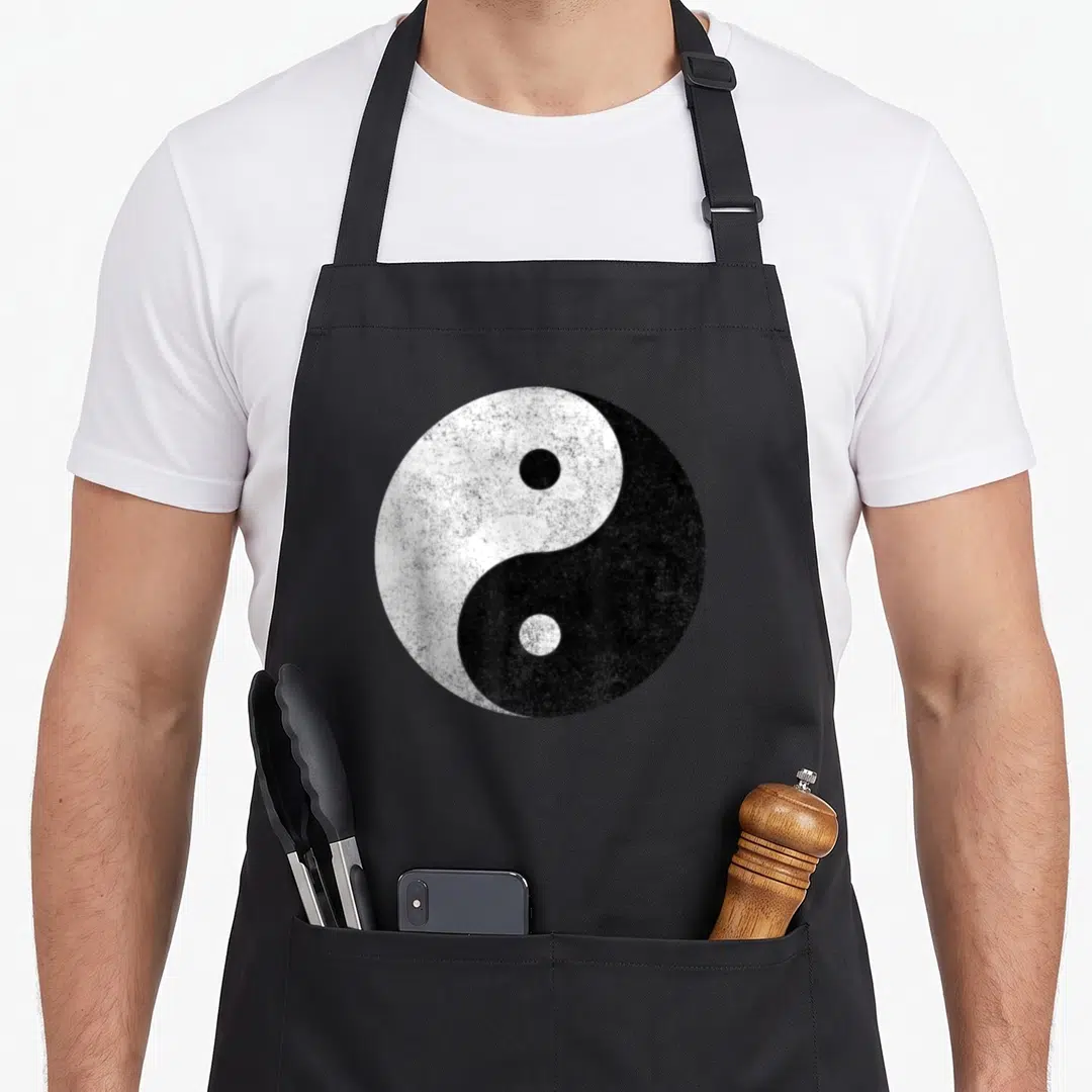 Symbol yin yoga apron - Distressed black and white yin yang symbol centered on grey background — shown on a black cotton canvas apron against a white background