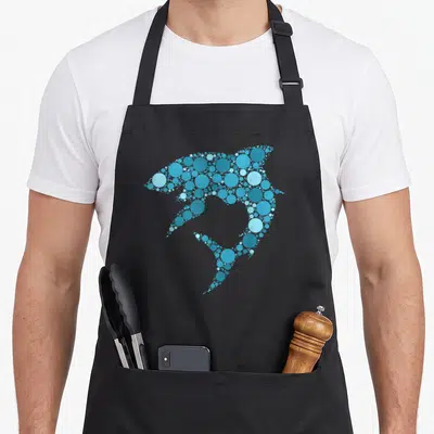 Blue polka dot apron - Dolphin silhouette formed by clusters of light, medium, and dark blue circles — shown on a black cotton canvas apron against a white background