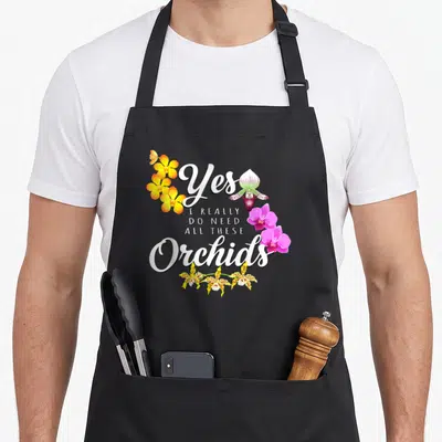 Orchid do i need an apron - Stacked white text Yes I Really Do Need All These Orchids with yellow, purple, pink flowers — shown on a black cotton canvas apron against a white background