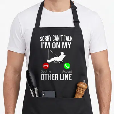 Reel fishing aprons - Fisherman silhouette with Sorry Can't Talk I'm On My Other Line text and red green phone buttons — shown on a black cotton canvas apron against a white background