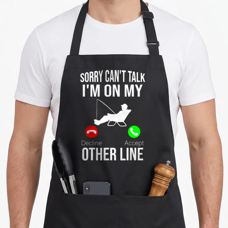 Reel fishing aprons - Fisherman silhouette with Sorry Can't Talk I'm On My Other Line text and red green phone buttons — shown on a black cotton canvas apron against a white background