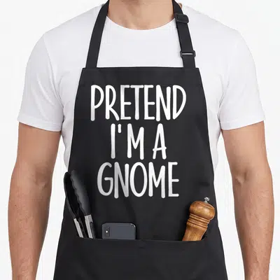 Gnome halloween apron - White PRETEND I'M A GNOME text stacked on black background — shown on a black cotton canvas apron against a white background