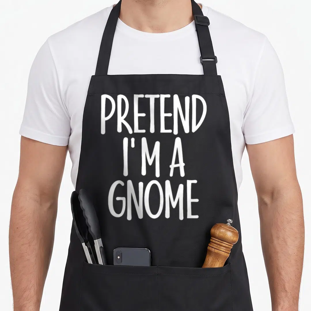Gnome halloween apron - White PRETEND I'M A GNOME text stacked on black background — shown on a black cotton canvas apron against a white background