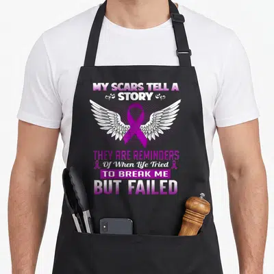 Epilepsy story of the apron - Purple awareness ribbon with white wings and text about scars telling a story of survival — shown on a black cotton canvas apron against a white background