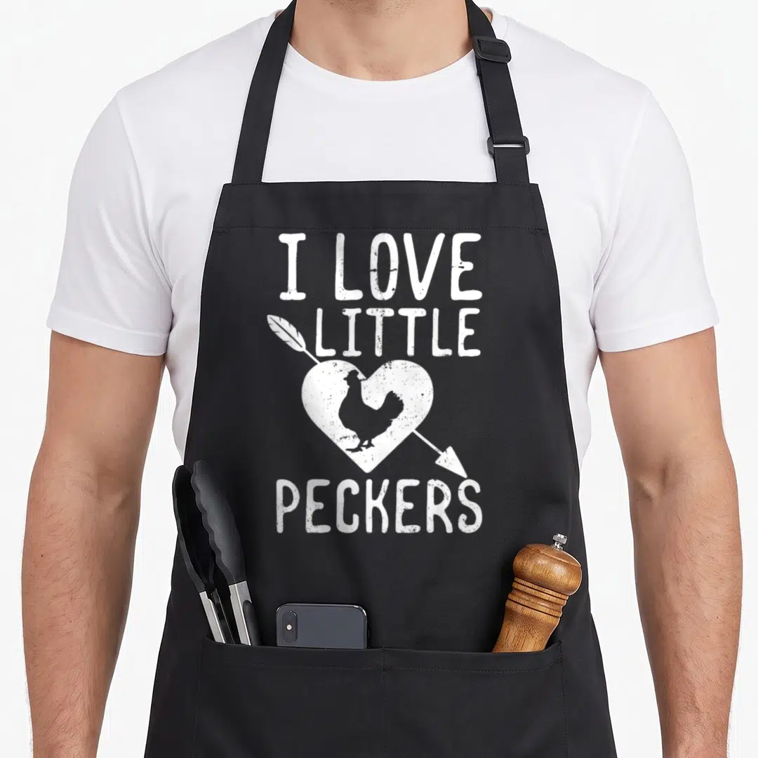 Funny pecker chicken apron - White distressed text I LOVE LITTLE PECKERS with chicken inside pierced heart — shown on a black cotton canvas apron against a white background