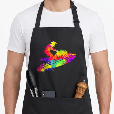 Sport jet girl apron - Multi-colored tie-dye splatter silhouette of a person riding a jet ski — shown on a black cotton canvas apron against a white background