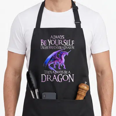 Alway yourself dragon apron - Purple dragon illustration between pink and white text reading always be yourself unless — shown on a black cotton canvas apron against a white background