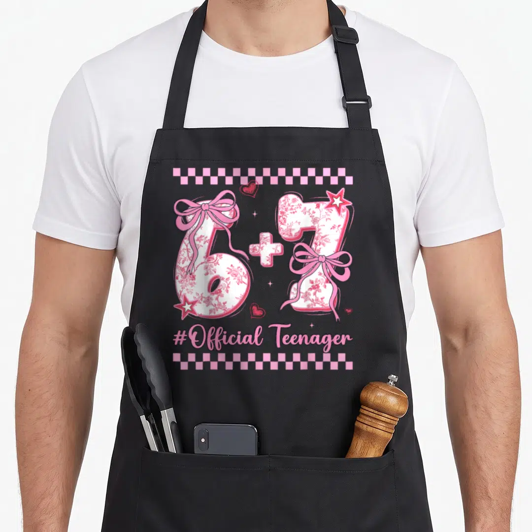 13th six birthday apron - Pink floral 6+7 numbers with bows and #Official Teenager text bordered by checkerboard strips — shown on a black cotton canvas apron against a white background