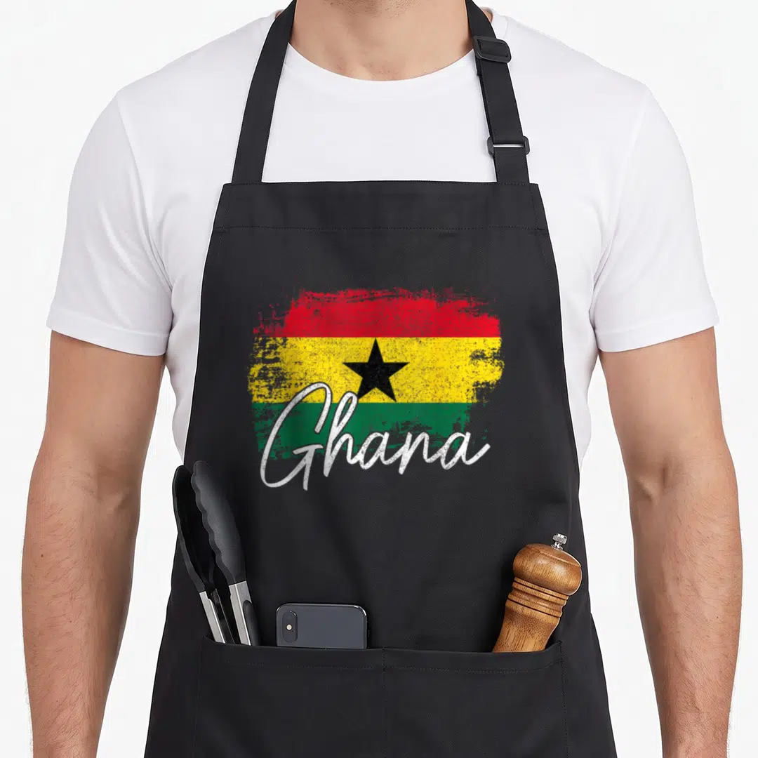 Ghana pride apron - Distressed Ghana flag with red yellow green stripes black star and white script text — shown on a black cotton canvas apron against a white background