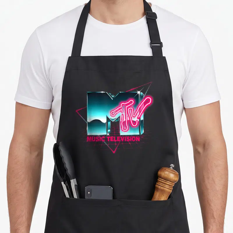Chrome 80s apron - Teal chrome 3D M with neon pink TV text and MUSIC TELEVISION lettering on a grid — shown on a black cotton canvas apron against a white background