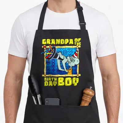 Squidward grandad aprons - Cartoon character in bamboo frame holding party horn with GRANDPA OF THE BIRTHDAY BOY text — shown on a black cotton canvas apron against a white background