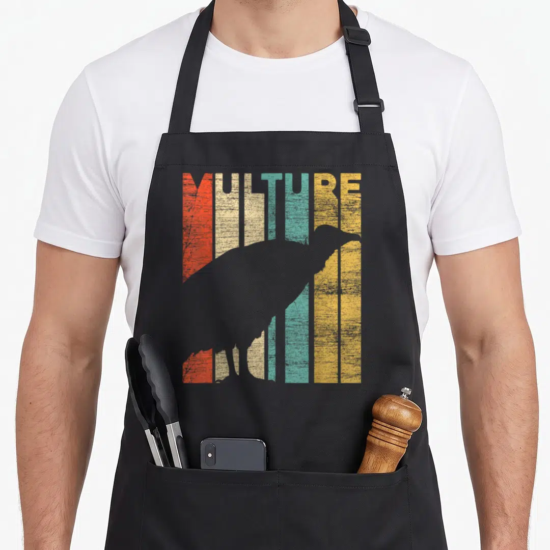 Funny vulture mom apron - Grey vulture silhouette overlapping vertical stripes in red, beige, teal, yellow, and grey — shown on a black cotton canvas apron against a white background