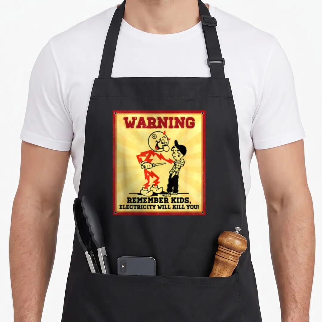Remember electrician apron - Vintage warning sign with electric monster holding knife and boy, red border — shown on a black cotton canvas apron against a white background