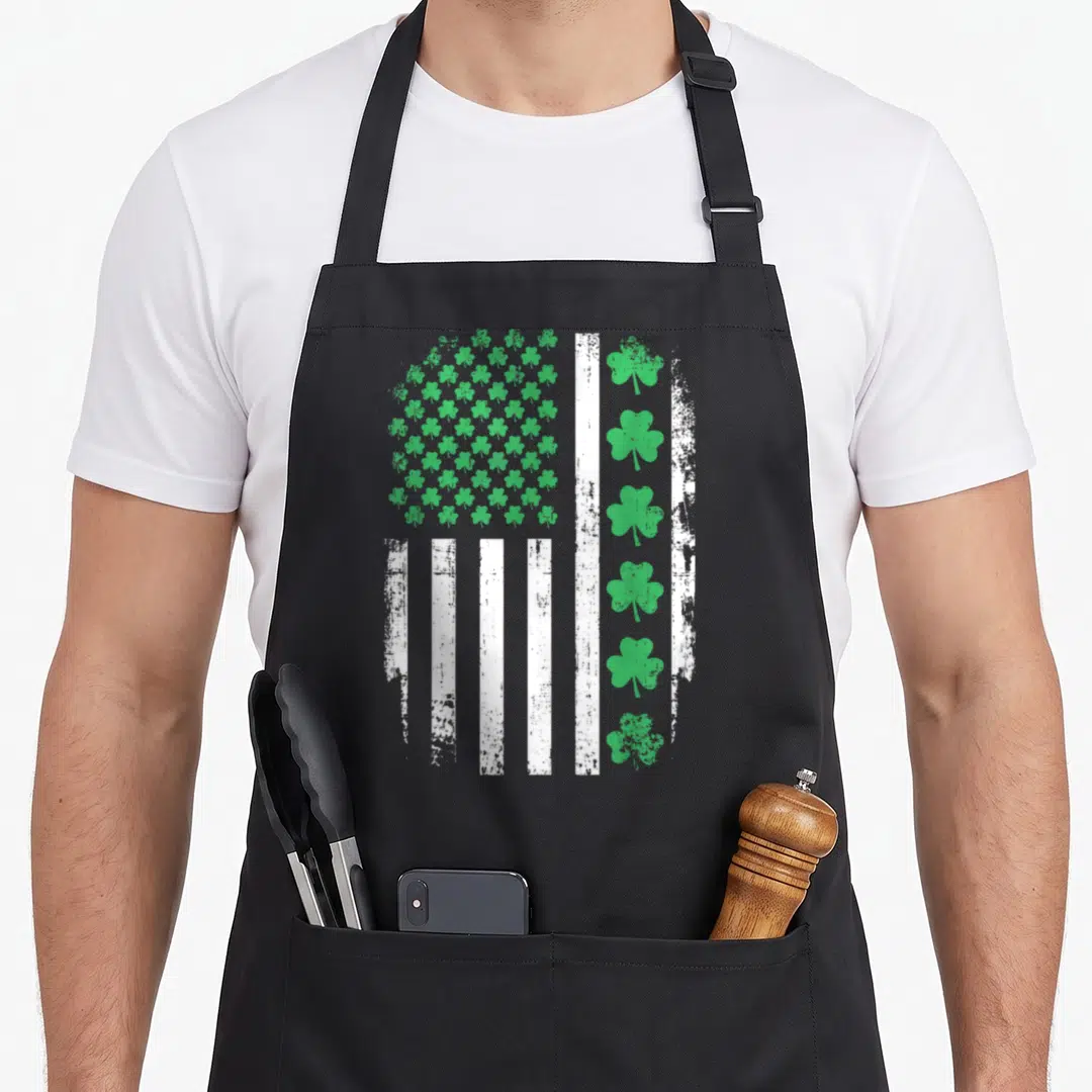 Shamrock st patrick day aprons - Distressed US flag with green shamrock grid and vertical white stripes — shown on a black cotton canvas apron against a white background